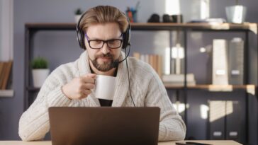 man holding a mug and working on a laptop at home