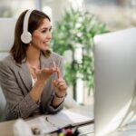 smiling woman with headphones working on a computer from home