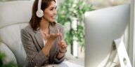 smiling woman with headphones working on a computer from home