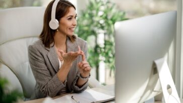 smiling woman with headphones working on a computer from home