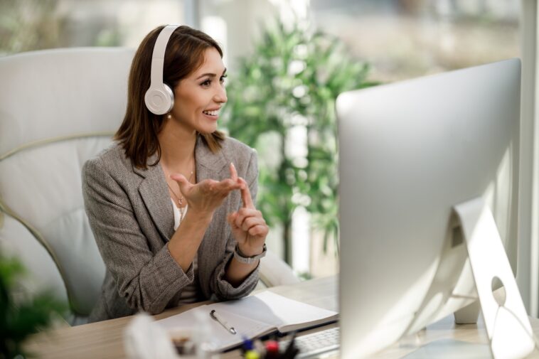 smiling woman with headphones working on a computer from home