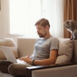 man sitting on a couch and working on a laptop