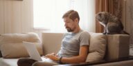 man sitting on a couch and working on a laptop