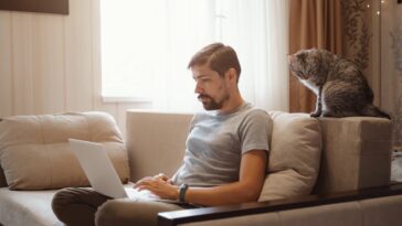 man sitting on a couch and working on a laptop