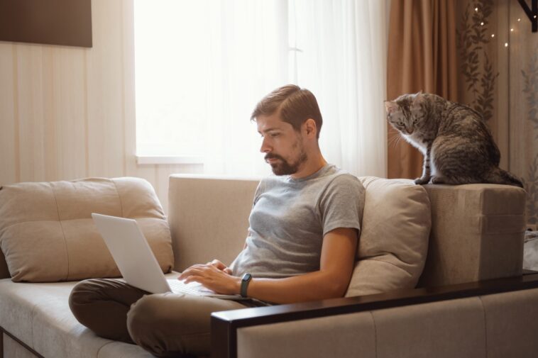 man sitting on a couch and working on a laptop