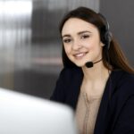 smiling girl with a headset working on a computer
