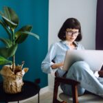 woman sitting in a chair at home with a laptop in her lap