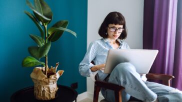 woman sitting in a chair at home with a laptop in her lap