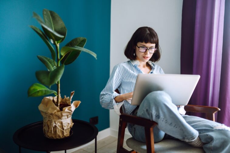 woman sitting in a chair at home with a laptop in her lap