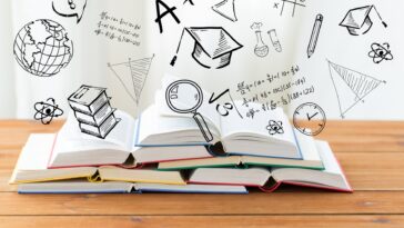 books on a wooden table with 3D education icons above them