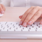 female hands using a white keyboard and computer mouse