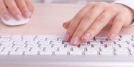 female hands using a white keyboard and computer mouse