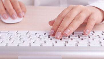 female hands using a white keyboard and computer mouse