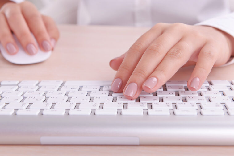 female hands using a white keyboard and computer mouse