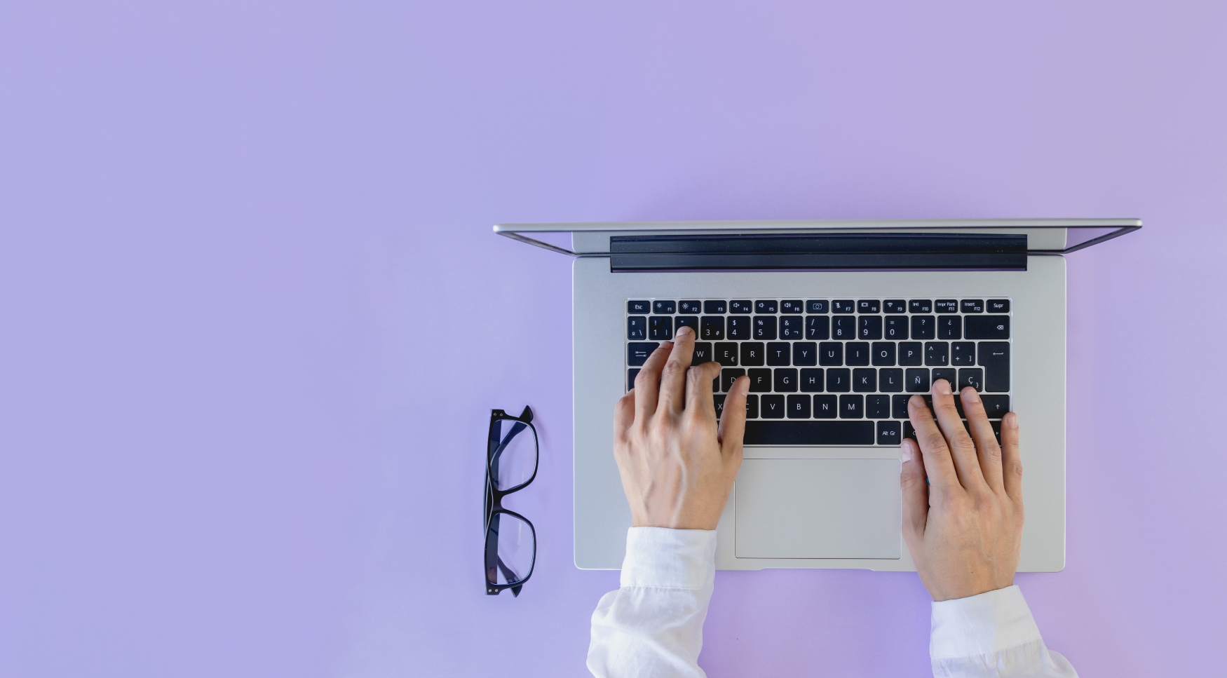 hands on a laptop with glasses next to it