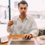 man working on a laptop drinking coffee