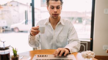 man working on a laptop drinking coffee