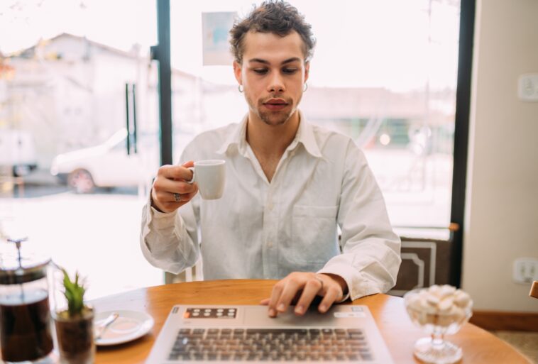 man working on a laptop drinking coffee