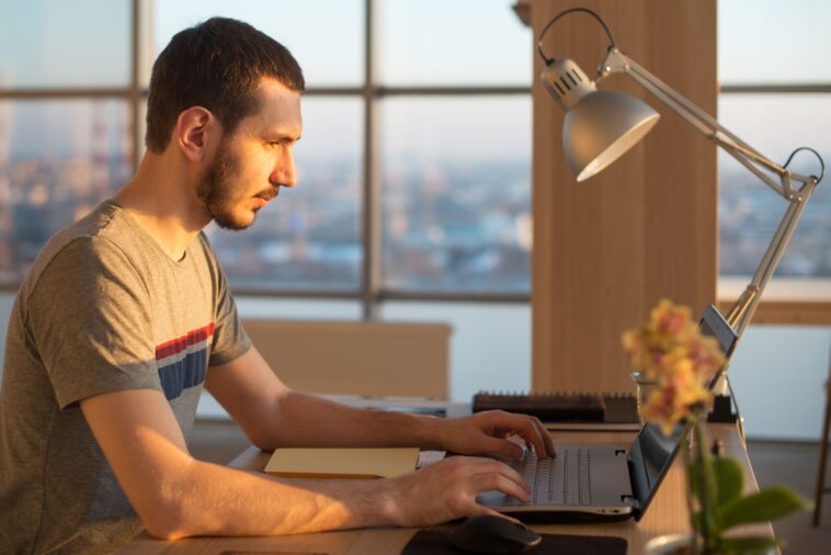 man working on a laptop at an office desk