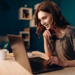 woman working on a laptop from home holding glasses