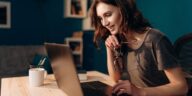 woman working on a laptop from home holding glasses