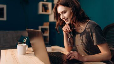 woman working on a laptop from home holding glasses