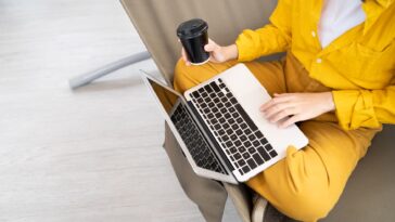 closeup of person using a laptop and drinking coffee