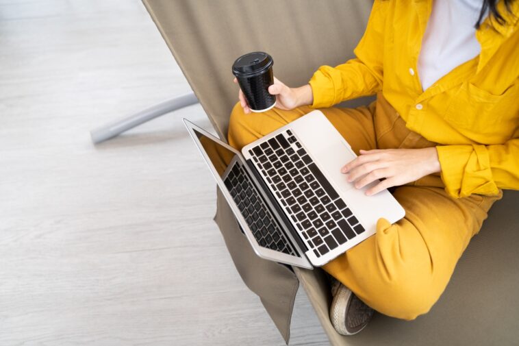 closeup of person using a laptop and drinking coffee