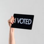 hand holding a sign that says "I voted"