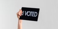 hand holding a sign that says "I voted"