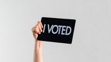 hand holding a sign that says "I voted"