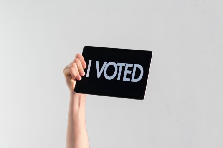 hand holding a sign that says "I voted"