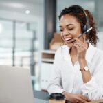 woman with a headset talking while using a laptop