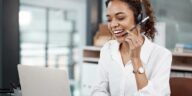 woman with a headset talking while using a laptop