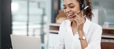 woman with a headset talking while using a laptop