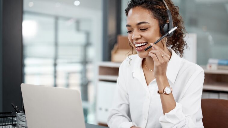 woman with a headset talking while using a laptop