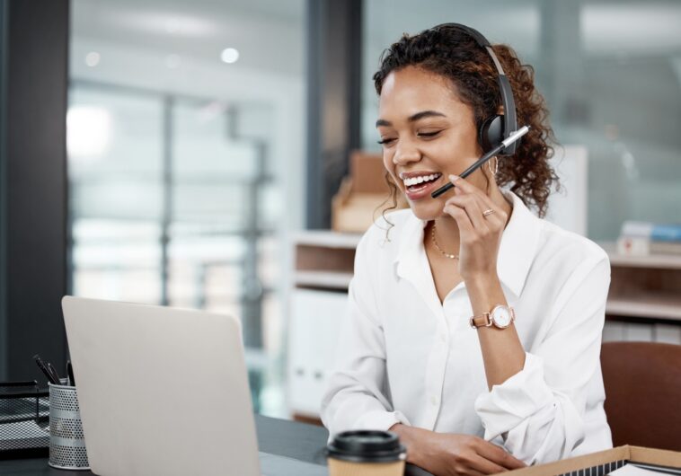 woman with a headset talking while using a laptop