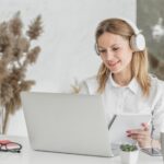 woman with headphones working on a laptop from home