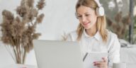 woman with headphones working on a laptop from home