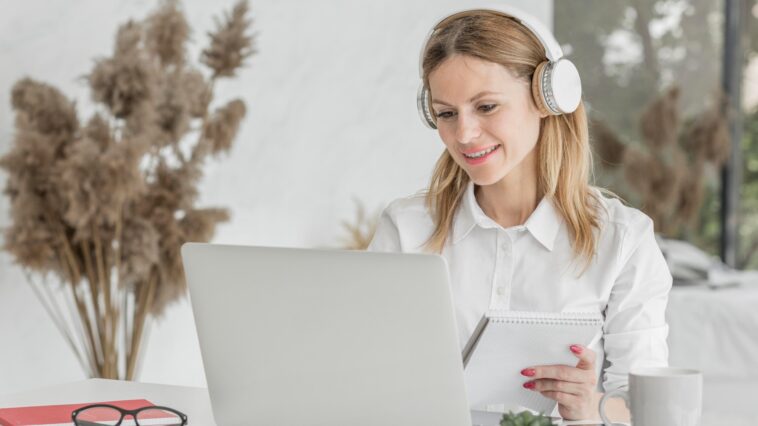 woman with headphones working on a laptop from home