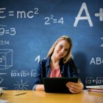 woman with a tablet in front of a blue chalkboard