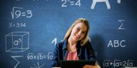 woman with a tablet in front of a blue chalkboard