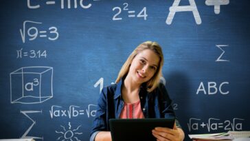 woman with a tablet in front of a blue chalkboard