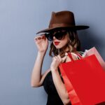 woman with a hat and sunglasses holding shopping bags