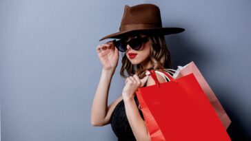 woman with a hat and sunglasses holding shopping bags