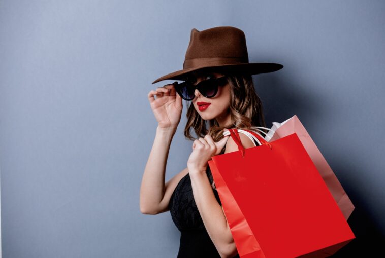 woman with a hat and sunglasses holding shopping bags