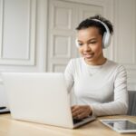 woman with headphones working on a laptop from home