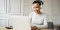 woman with headphones working on a laptop from home