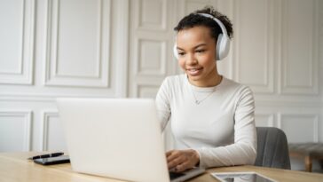 woman with headphones working on a laptop from home