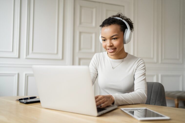 woman with headphones working on a laptop from home